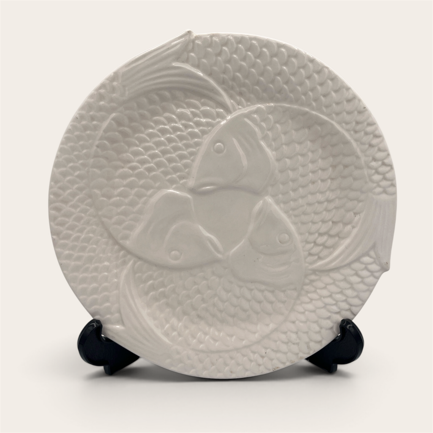 Single white embossed fish ceramic plate displayed on stand, front view