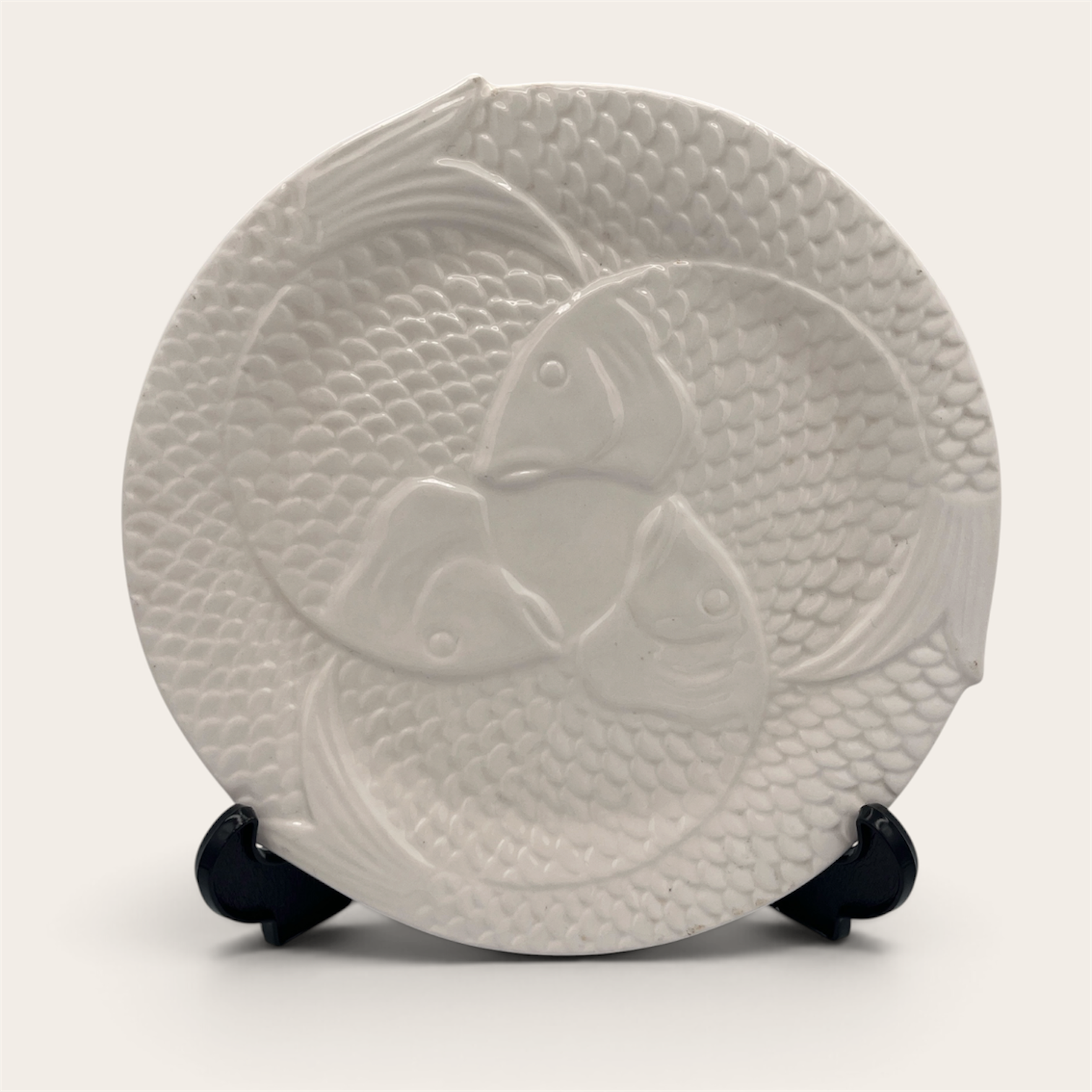 Single white embossed fish ceramic plate displayed on stand, front view